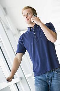 Man standing in corridor smiling using cellular phone