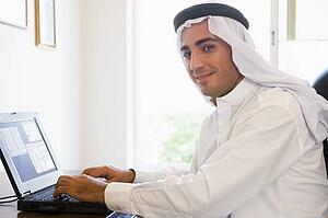 Man in office with laptop smiling (high key/selective focus)