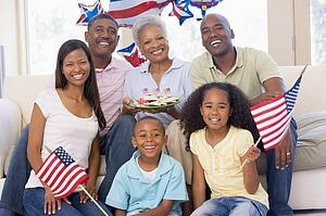 Family in living room on fourth of July with flags and cookies smiling
