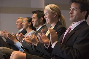 Five businesspeople applauding and smiling in presentation room
