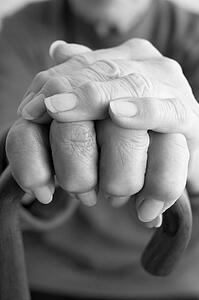 Close-Up Of Elderly Persons Hand Resting On Walking Cane