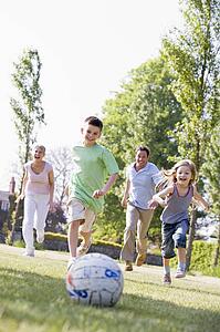 Family outdoors playing soccer and having fun