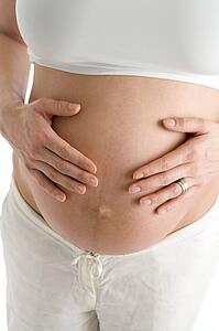 Pregnant woman holding exposed belly
