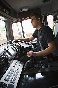 Fireman in fire engine holding steering wheel