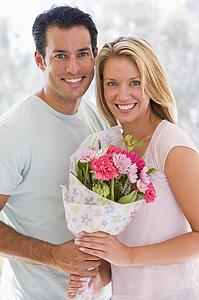 Husband and wife holding flowers and smiling
