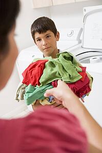 Young Boy Holding A Pile Of Laundry