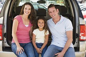 Family sitting in back of van smiling