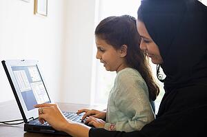 Mother and daughter in office with laptop smiling (high key/selective focus)