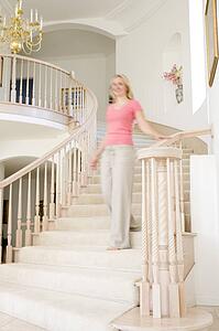 Woman coming down staircase in luxurious home