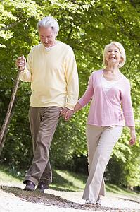 Couple walking on path in park holding hands and smiling