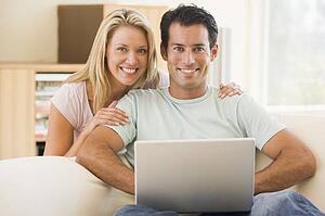 Couple in living room using laptop smiling