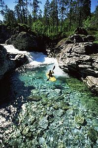 Kayaker in calm water near waterfall (far away)
