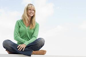 Blonde woman in a green sweater sitting outdoors