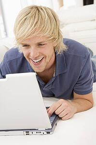 Man in living room with laptop smiling