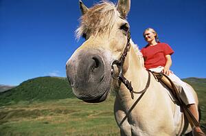 Woman outdoors riding horse and smiling (fisheye)