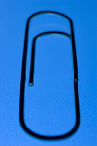 Close Up Of A Blue Paperclip, Against A Blue Background