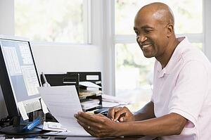 Man in home office using computer and smiling