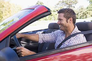 Man driving convertible car smiling