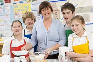 Students preparing ingredients in cooking class with teacher