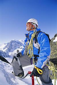 Mountain climber coming up snowy mountain smiling