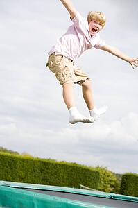 Young boy jumping on trampoline smiling