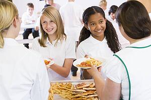 Students in cafeteria line being served by lunch ladies
