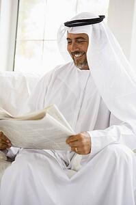 Man sitting indoors with newspaper smiling (high key/selective focus)