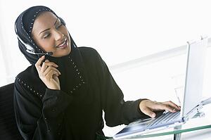 Woman wearing headset with laptop smiling (high key/selective focus)