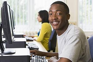 Man sitting at a computer terminal with woman in background (selective focus/high key)