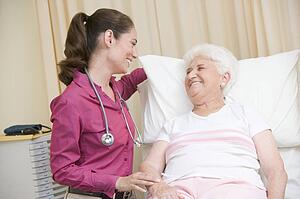 Doctor giving checkup to woman in exam room smiling