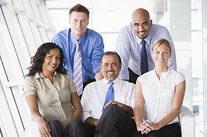 Five businesspeople indoors smiling (high key/selective focus)