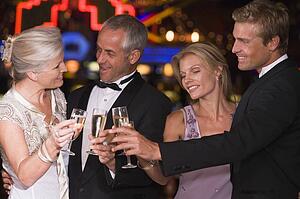 Two couples in casino toasting champagne smiling (selective focus)