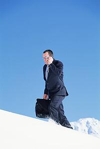 Businessman outdoors on snowy mountain using cellular phone