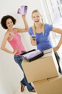Two women with paint swatches in new home smiling
