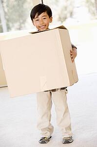 Young boy with box in new home smiling