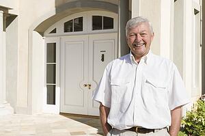 Senior man standing outside his home