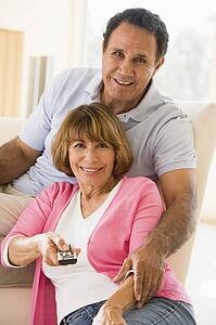 Couple in living room with remote control smiling
