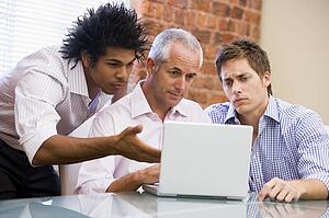 Three businessmen sitting in office with laptop