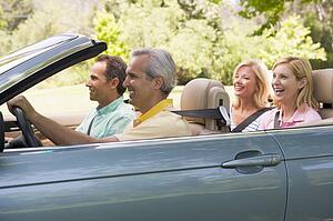 Two couples in convertible car smiling