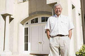 Senior man standing outside his home