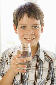 Young boy indoors drinking water smiling