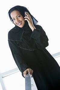 Woman indoors using cellular phone and smiling (high key/selective focus)