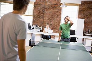 Two men in office space playing ping pong
