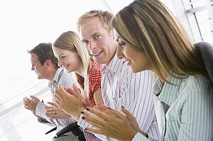 Four businesspeople applauding indoors smiling