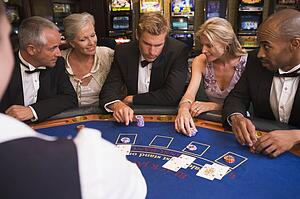 Five people in casino playing blackjack and smiling (selective focus)