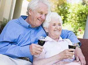Senior couple sitting outdoors having a glass of red wine