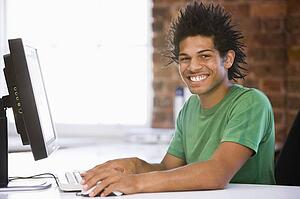 Businessman in office typing on computer smiling