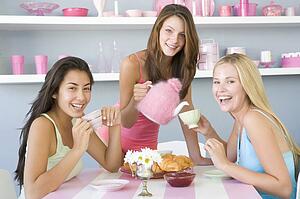 Three young woman sitting at a table having tea and a snack