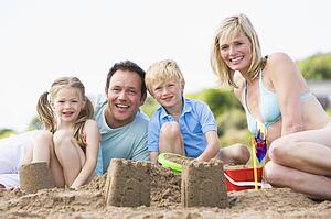 Family on beach making sand castles smiling
