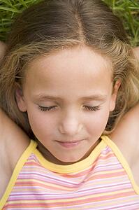 Young Girl Lying Down On The Grass